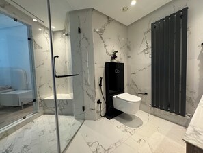 Um banheiro moderno com chuveiro em cabine de vidro, vaso sanitário e armário preto.