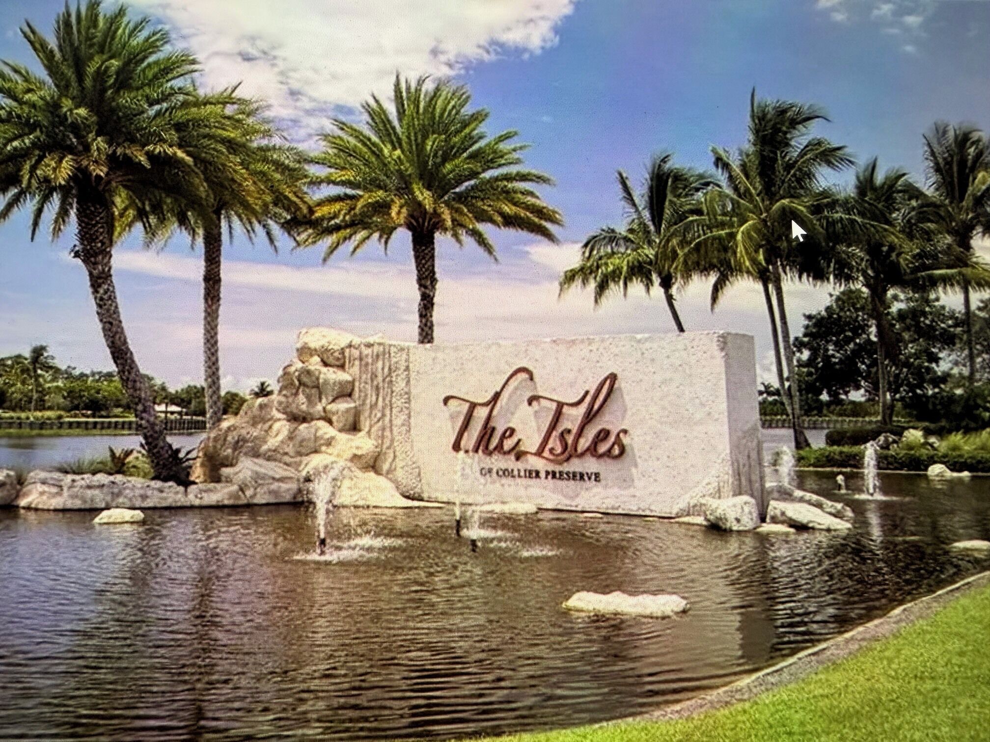A sign for The Isles of Collier Preserve with a water feature in the foreground.
