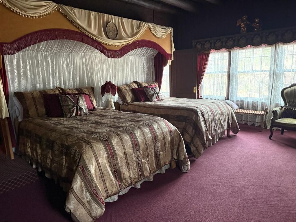 A bedroom with two beds, a canopy bed, and a chair.