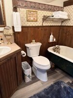 Un bagno con un mobile vanitario in legno, un water, una vasca da bagno e uno specchio.
