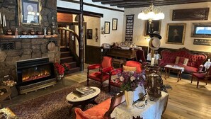 Una sala de estar acogedora con chimenea, sillones tapizados en rojo, una mesita de centro y un sofá rojo.