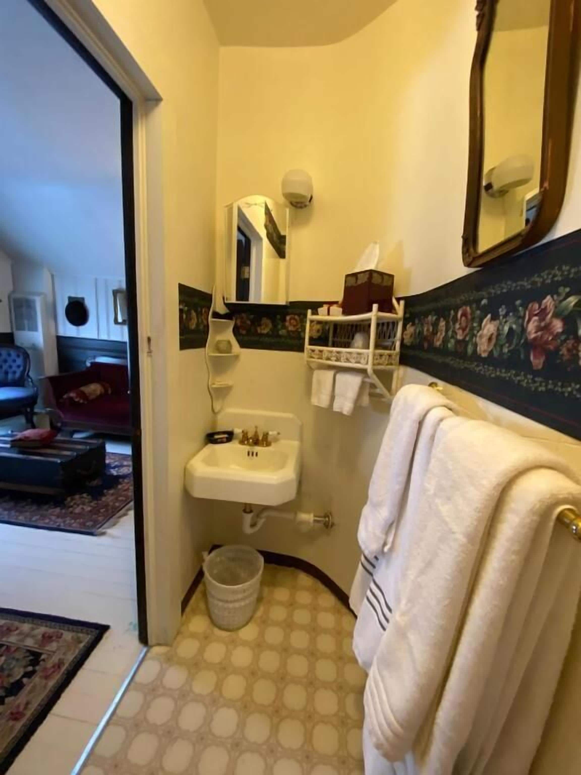 A bathroom with a sink, mirror, towel rack, and a patterned floor.