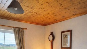 Een gezellige woonkamer met een geruite bank, fauteuil en een lamp op een houten vloer.