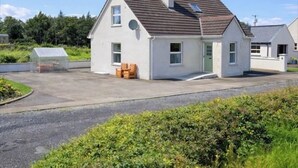 Een gelijkvloers huis met zadeldak, een schotelantenne en een klein terras met houten stoelen.