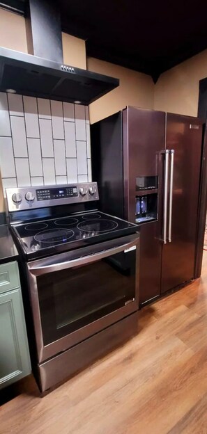 Una cocina con estufa de acero inoxidable, horno y dispensador de agua empotrado.