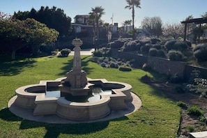 A landscaped garden with a central fountain, surrounded by well-maintained grass and various shrubs. - Casa Marieta, a place of peace and tranquility. (B.C.)