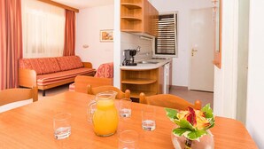 Ett kompakt bostadsutrymme med en matplats, ett litet kök och en soffa.