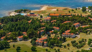 Ett flygbildsbild av ett bostadsområde vid kusten med hus, en strand och en swimmingpool.