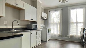 A modern kitchen with white cabinets, a built-in microwave, and a washing machine.