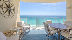 A balcony with a view of the ocean, furnished with wicker chairs and a small table. - Boardwalk Beauty: stunning 17th floor condo with private balcony & bunk room (Panama City Beach)