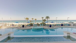 A pool area with a view of the beach, lounge chairs, and umbrellas. - Boardwalk Beauty: stunning 17th floor condo with private balcony & bunk room (Panama City Beach)