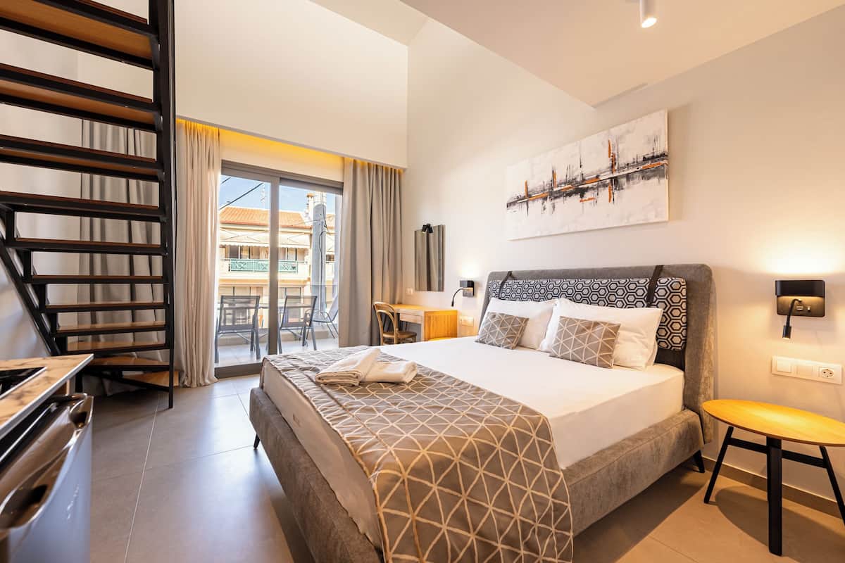 Een moderne hotelkamer met een bed, een bureau, een stoel, een bijzettafeltje en een trap.