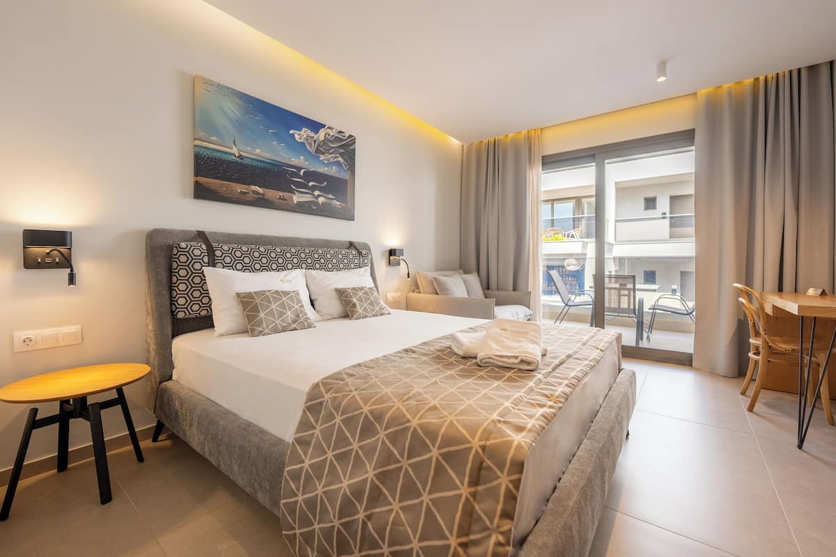 Hotelkamer met een groot bed, een bureau, een stoel, een schilderij en uitzicht.