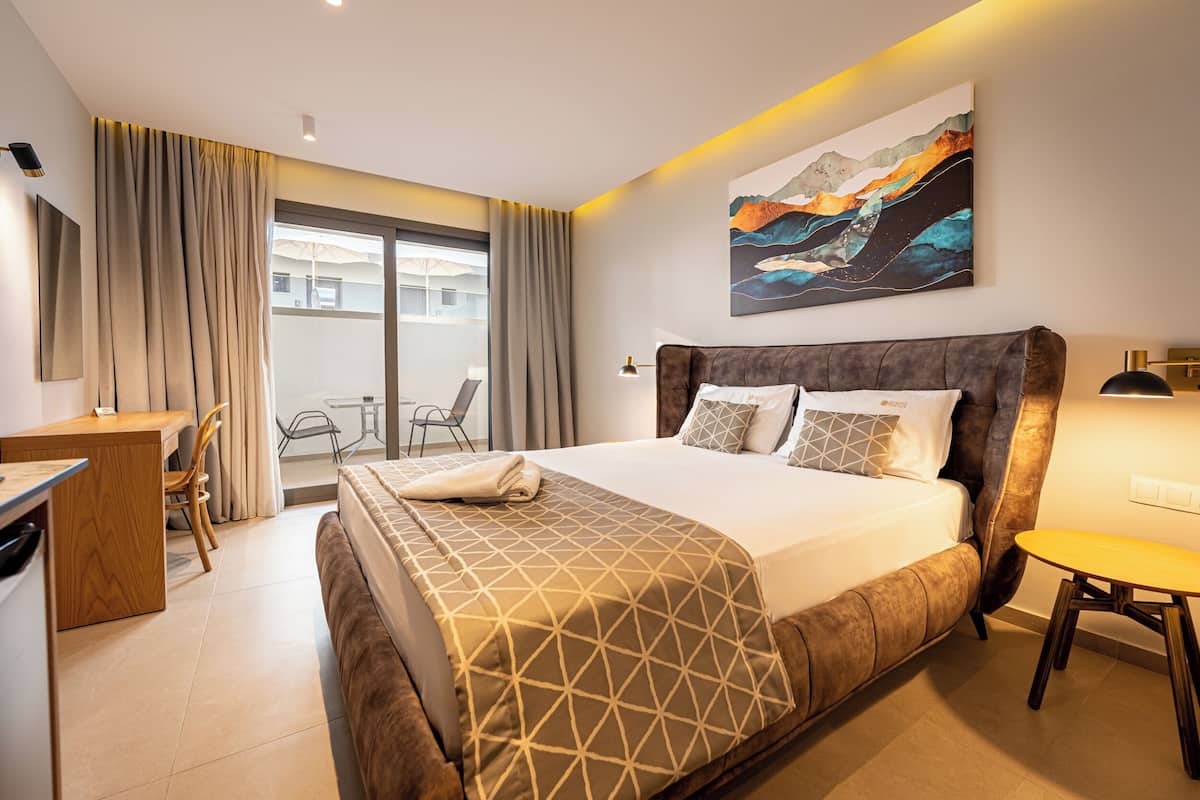 Een hotelkamer met een groot bed, een bureau, een stoel, een klein tafeltje en uitzicht op buiten.