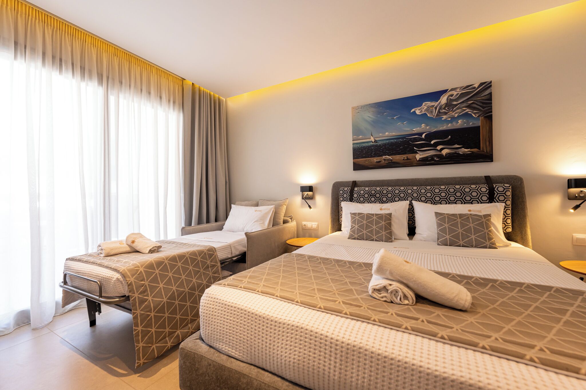 Ein Hotelzimmer mit zwei Betten, einem Gemälde und Meerblick.