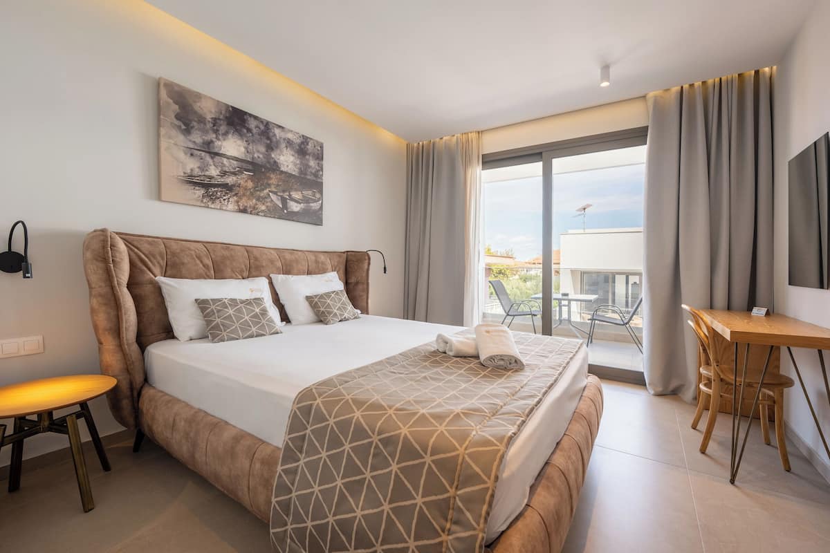 Een moderne hotelkamer met een groot bed, een bureau en een balkon met uitzicht.