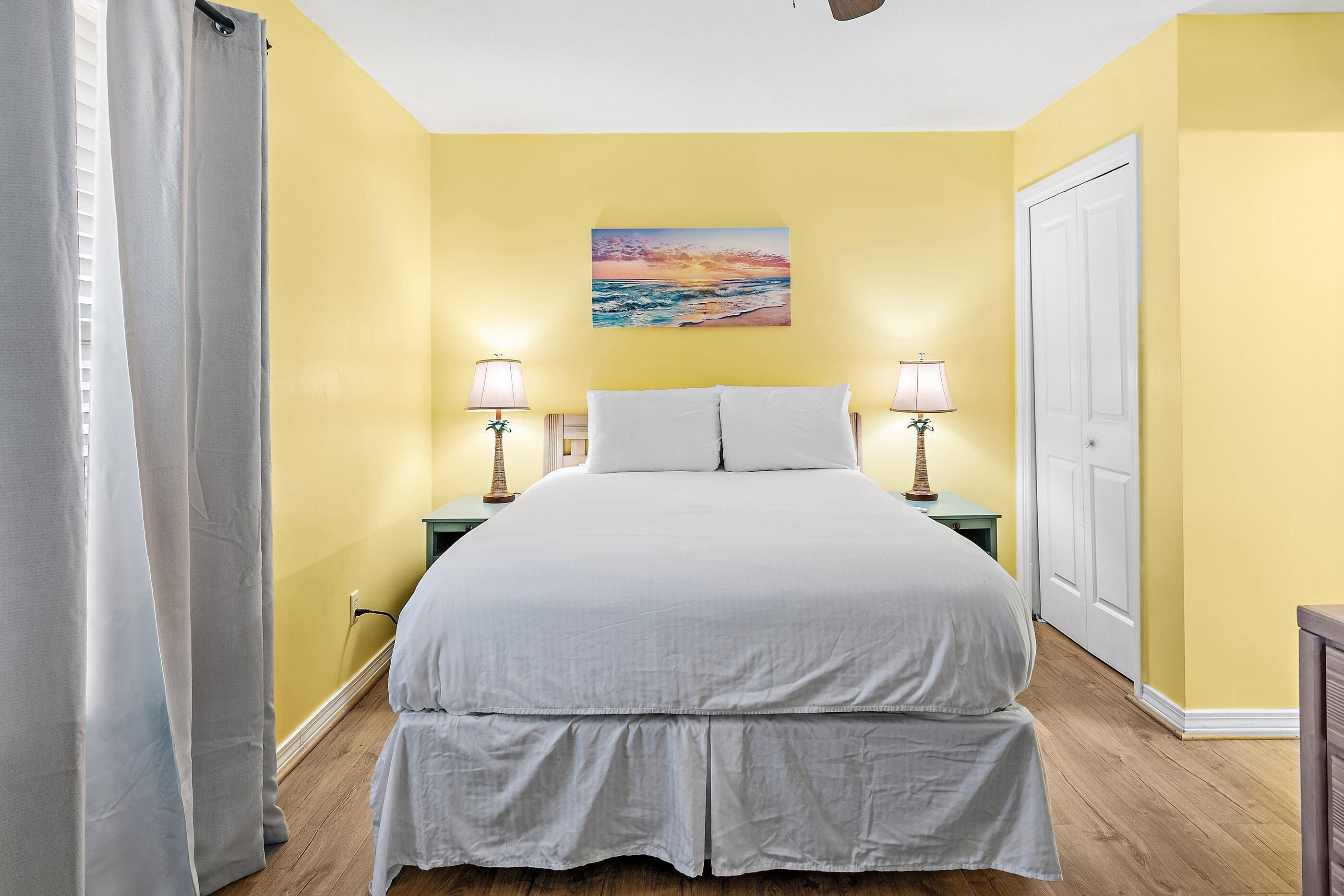 Een slaapkamer met een bed, twee bedlampen, een schilderij aan de muur en een deur.