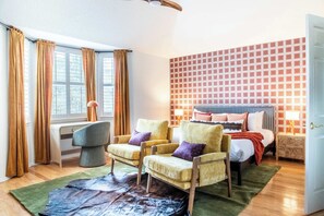 A bedroom with a bed, two armchairs, a desk, and a window with curtains. - Upscale Escape • Pool, Hot Tub, Game Room, Firepit (San Antonio)