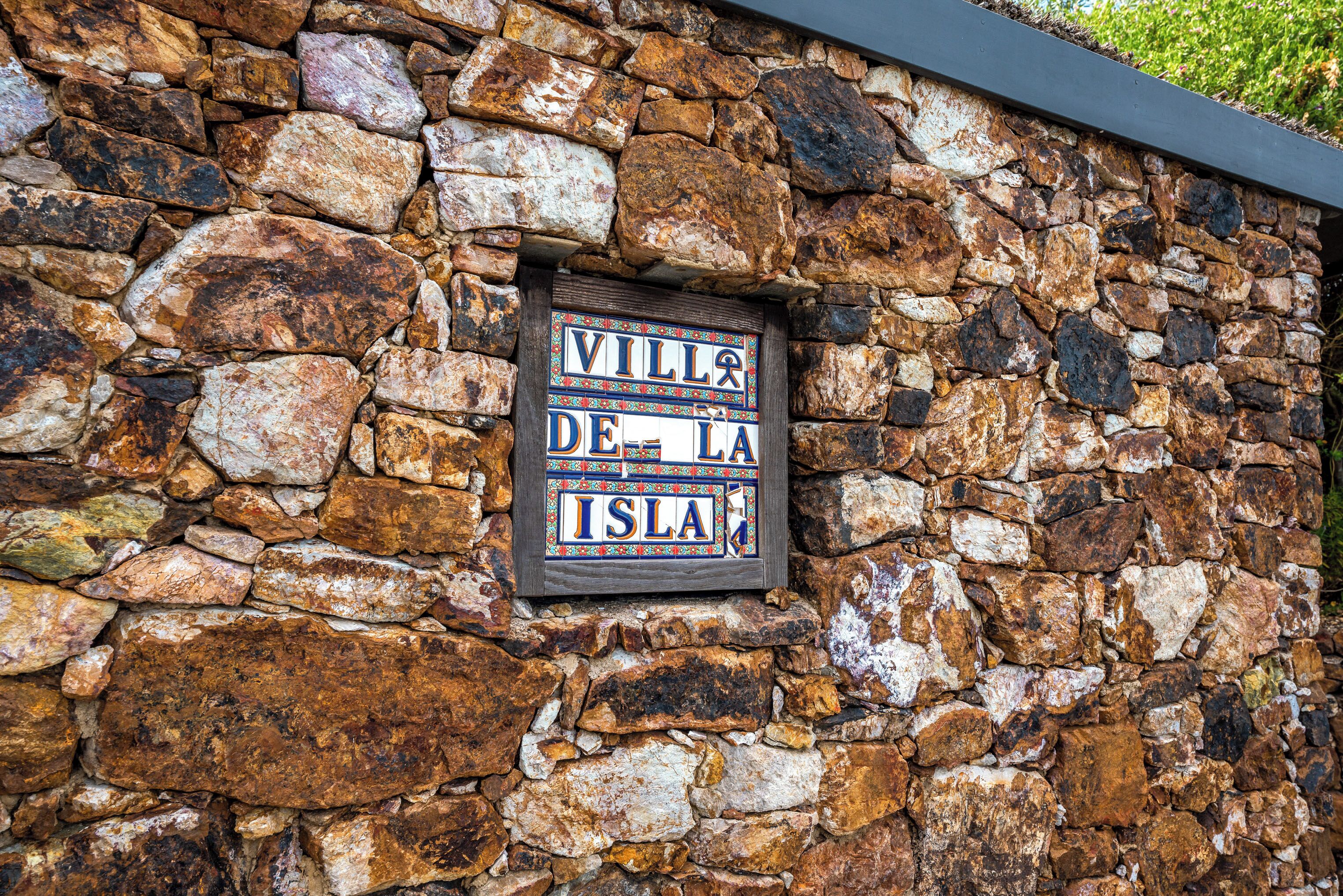 Un mur de pierre sur lequel est apposée une plaque portant l’inscription « Villa de la Isla ».