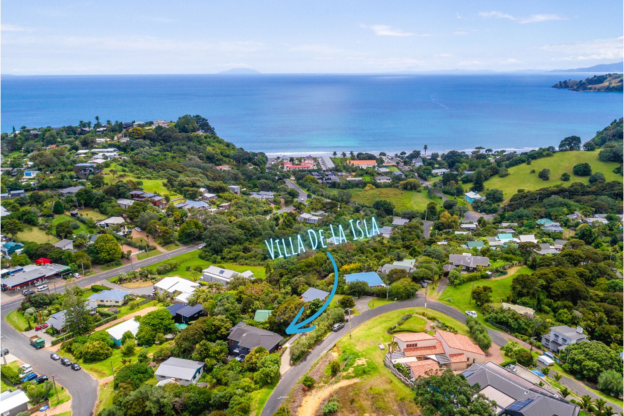 An aerial view of Villa de la Isla, featuring a coastal landscape with residential buildings, roads, and lush greenery.