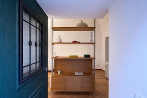 Ein Flur mit Holzschrank und Regalen, einer Tür mit Glasfenster und einer Deckenleuchte.
