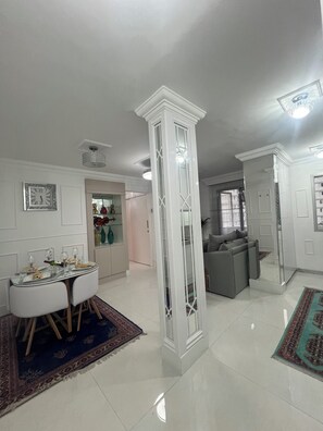 Amplia sala de estar con una mesa de comedor lista para cuatro, un sofá y un pilar decorativo.