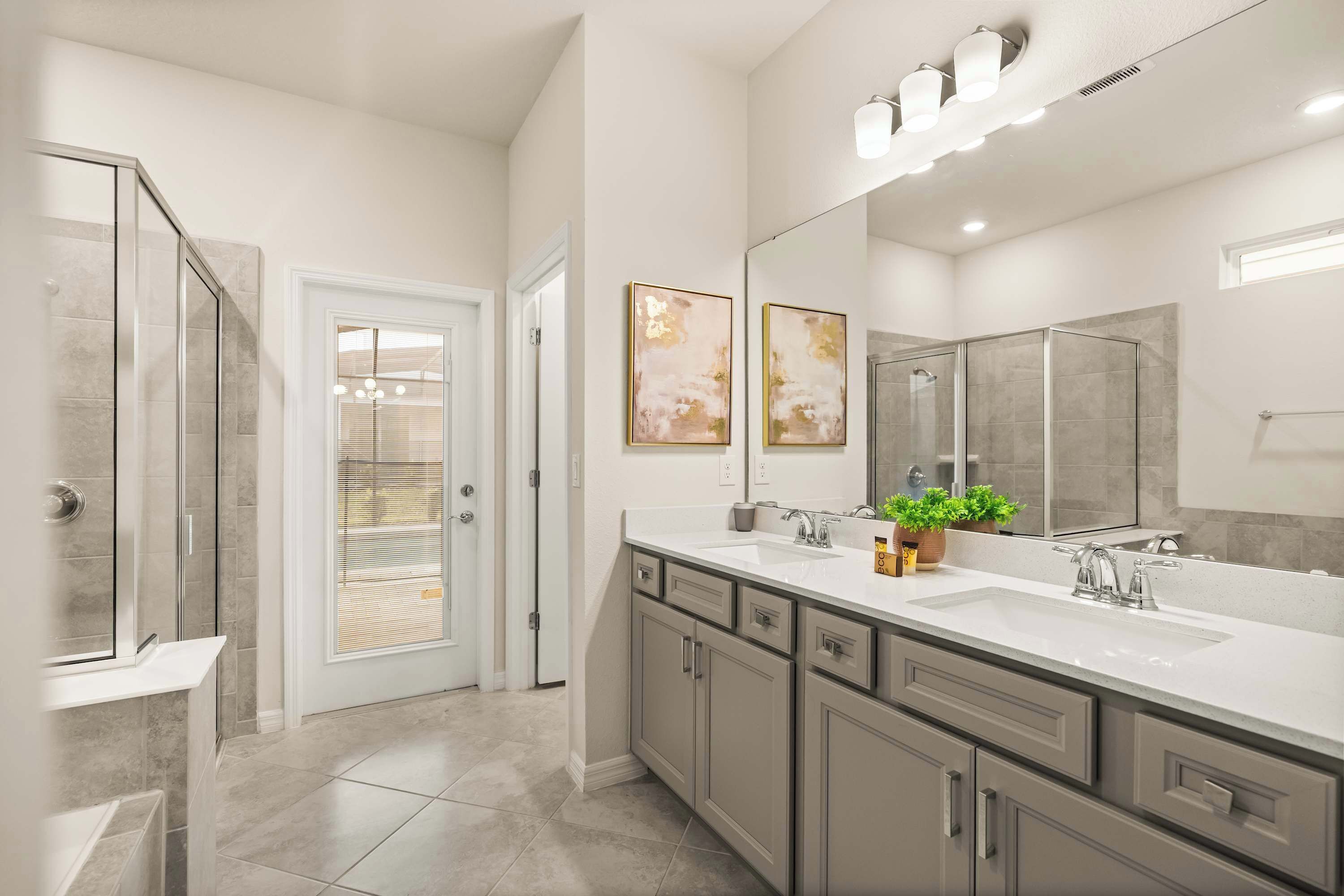 A modern bathroom with a glass shower enclosure, a double sink vanity, and a large mirror.