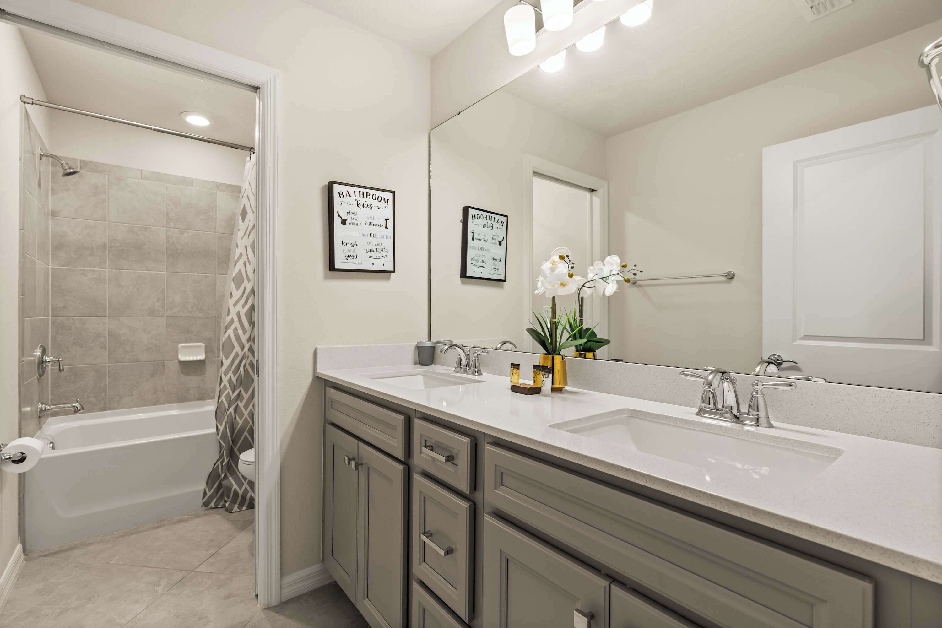 A bathroom with a bathtub, two sinks, a mirror, and a shower curtain.