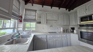 Een keuken met witte kastjes, een roestvrijstalen spoelbak en een ingebouwde oven.