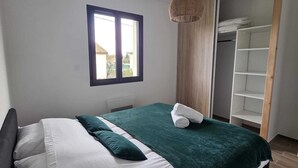 A bedroom with a bed, a window, a hanging light fixture, and a built-in wardrobe. - House Rochemaure (Rochemaure)