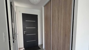 A hallway with a black door, a wooden wardrobe, and a white wall. - House Rochemaure (Rochemaure)