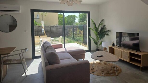 A modern living room with a sofa, a coffee table, a TV, and a sliding glass door leading to an outdoor area. - House Rochemaure (Rochemaure)