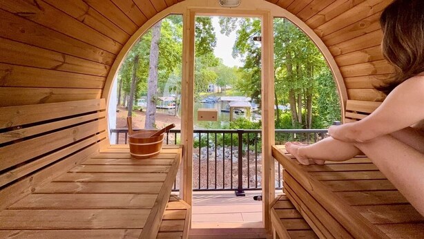 Uma sauna de madeira com bancos e vista para um lago e edifícios.