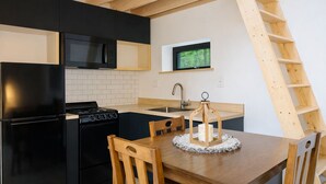 Eine Küche mit schwarzen Geräten, einem Holztisch und einem an der Wand befestigten Fernseher.