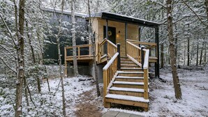 Eine Holztreppe führt zu einer Hütte in einem verschneiten Wald.