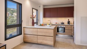 Una cocina moderna con armarios de madera, horno empotrado y un amplio ventanal con vistas al entorno.