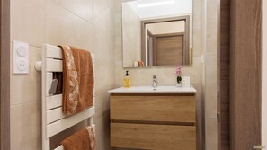A bathroom with a white sink, wooden vanity, and a towel rack with patterned towels.