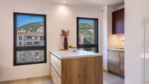 Una cocina moderna con ventanas amplias, una isla de madera y vistas a una zona residencial.