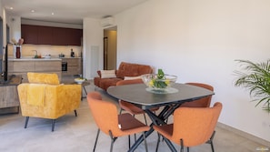 Un salon moderne avec une table à manger, des chaises orange et un vase en verre rempli de fleurs.