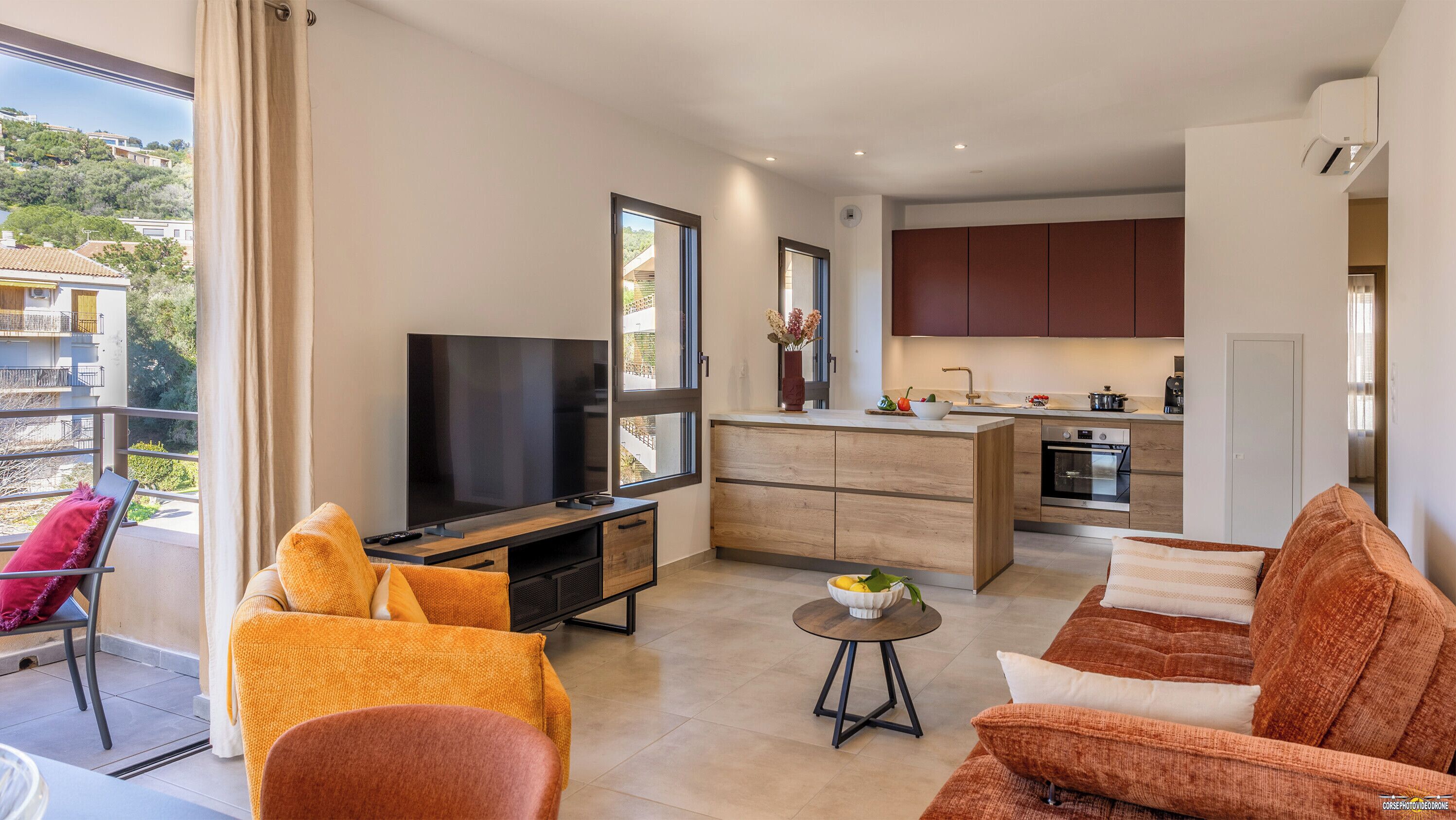 Eine moderne Wohnung mit Balkon, Flachbildfernseher, Küchenzeile und Essbereich.
