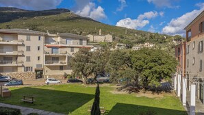 Un quartier résidentiel avec des immeubles à plusieurs étages, une cour verdoyante et une colline sur laquelle se dresse une tour en arrière-plan.