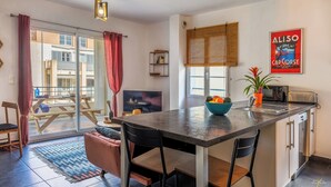 Une cuisine moderne dotée d’un îlot central, d’un coin repas avec un canapé et d’une vue sur le balcon extérieur.
