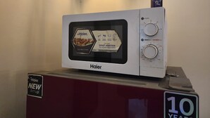 A Haier microwave oven with a '10 years' anniversary plaque, placed on a red cabinet.