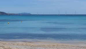 Ein Strand mit klarem Wasser, Booten und einem entfernten Berg.