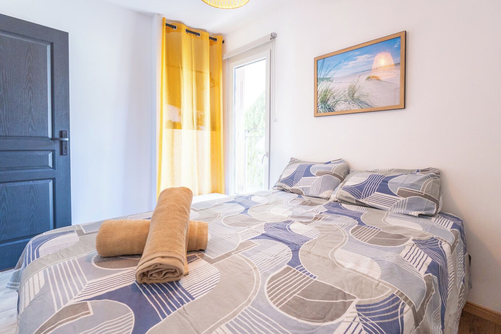 Une chambre à coucher avec un lit, une serviette enroulée, un tableau et une porte.