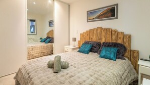 Un dormitorio con una cama grande, cabecera de madera, un espejo y un cuadro en la pared.