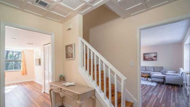 A spacious living area with a wooden floor, a white staircase, and a seating area with two sofas. - The Marsh House (Brunswick)