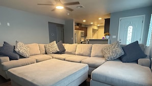 Ein modernes Wohnzimmer mit Ecksofa, dunklem Holzboden und Einbaustrahler.