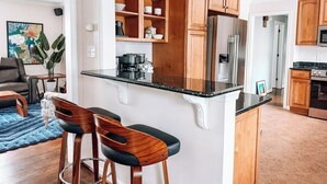 Une cuisine moderne avec des meubles en bois, un réfrigérateur en acier inoxydable et un plan de travail noir.