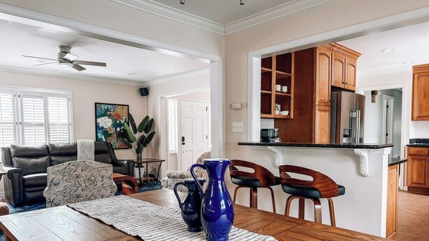 Un salon spacieux avec une table à manger en bois, des vases bleus et un canapé en cuir noir.